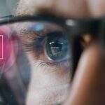 Närbild på man som analyserar cybersäkerhetsdata genom smarta glasögon, symboliserar Check Point Researchs övervakning av cyberhot.
